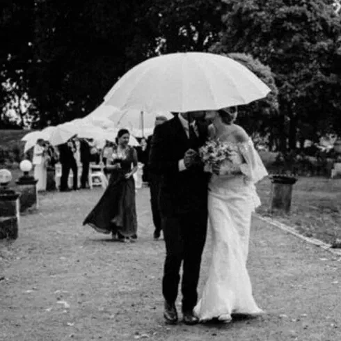 Schwarz-Weiß-Aufnahme eines Brautpaares unter einem Regenschirm.