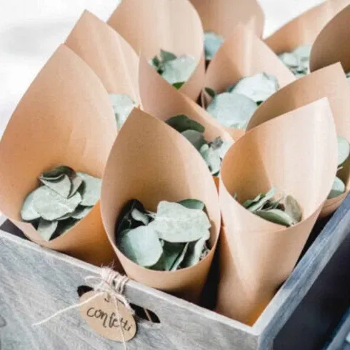 Eine rustikale Holzkiste gefüllt mit Papiertüten voller Eukalyptusblätter, bereit für den Auszug des Brautpaares.