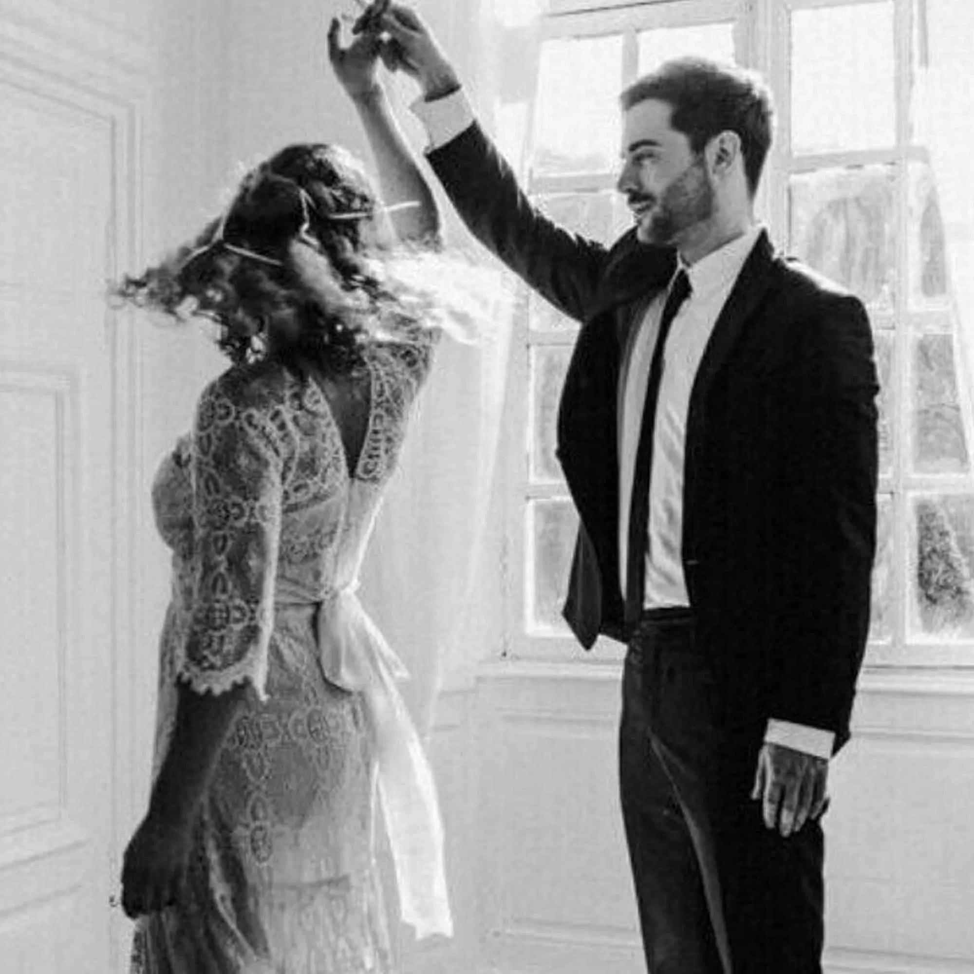 Ein frisch vermähltes Paar tanzt in einem lichtdurchfluteten Raum. Der Bräutigam hebt den Arm, während die Braut sich schwungvoll dreht.