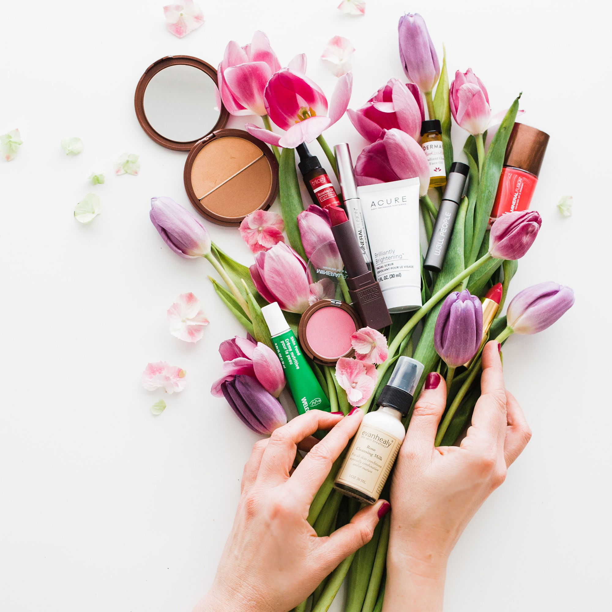 Make-up-Produkte umgeben von violetten Tulpenblüten, eine wunderschöne Darstellung von Beauty-Essentials für den Hochzeitstag.