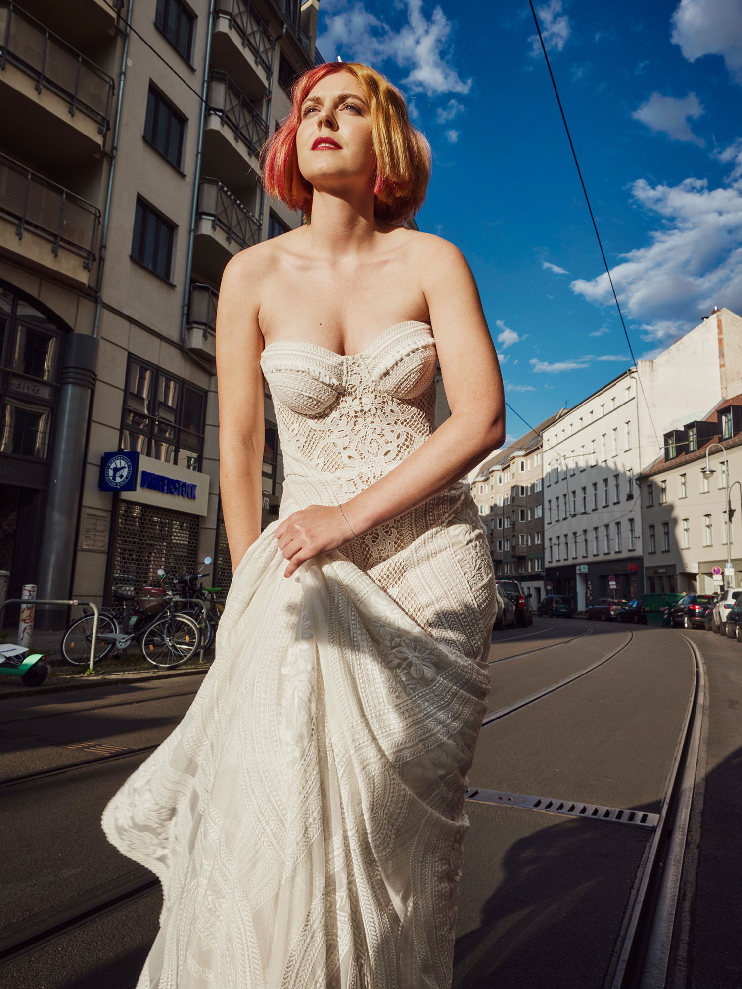 Braut im Hochzeitskleid mit rot gelb gefärbten Haaren posiert in den Straßen