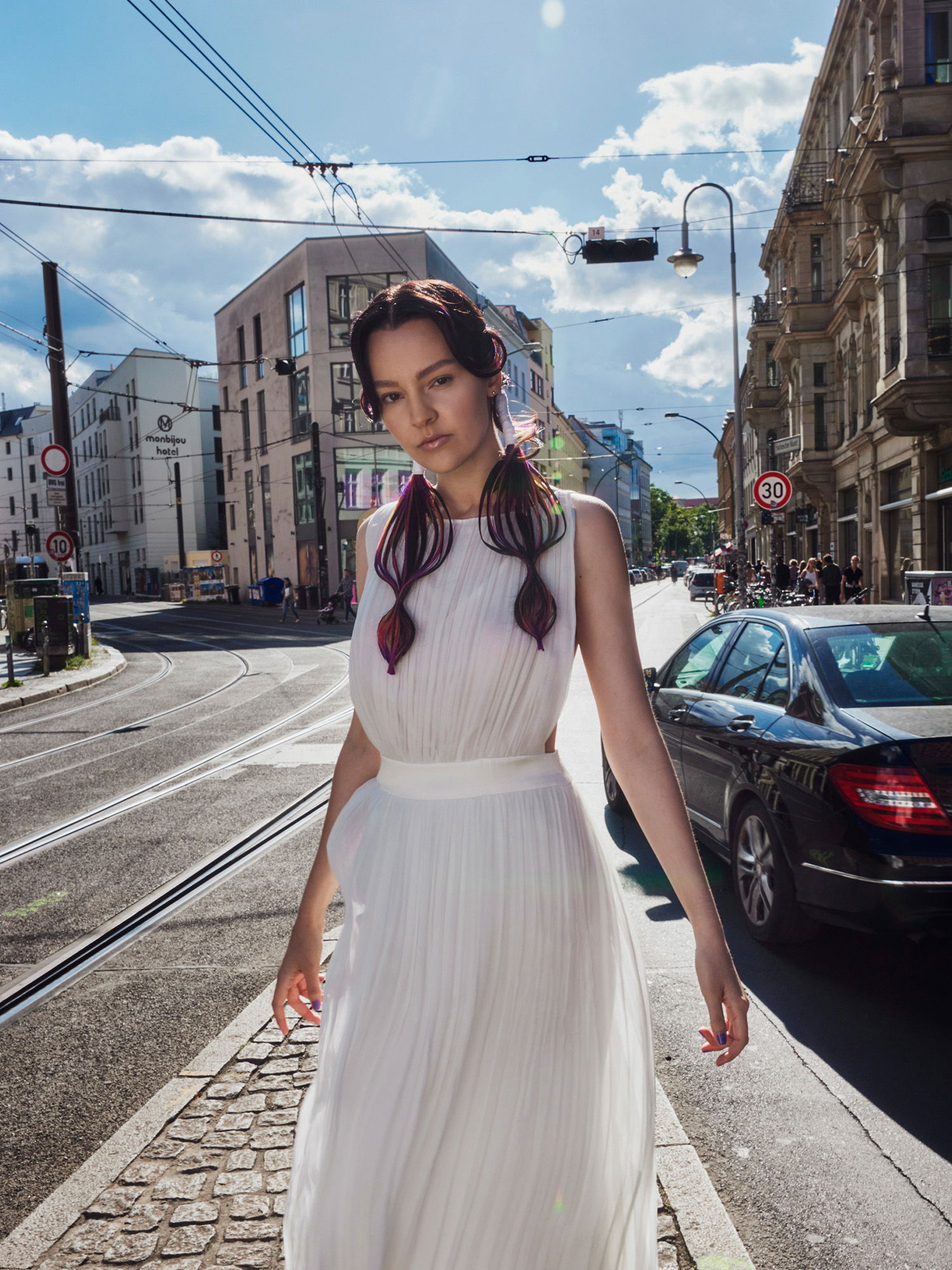 Braut im Hochzeitskleid mit bunt gefärbten Haaren posiert in den Straßen