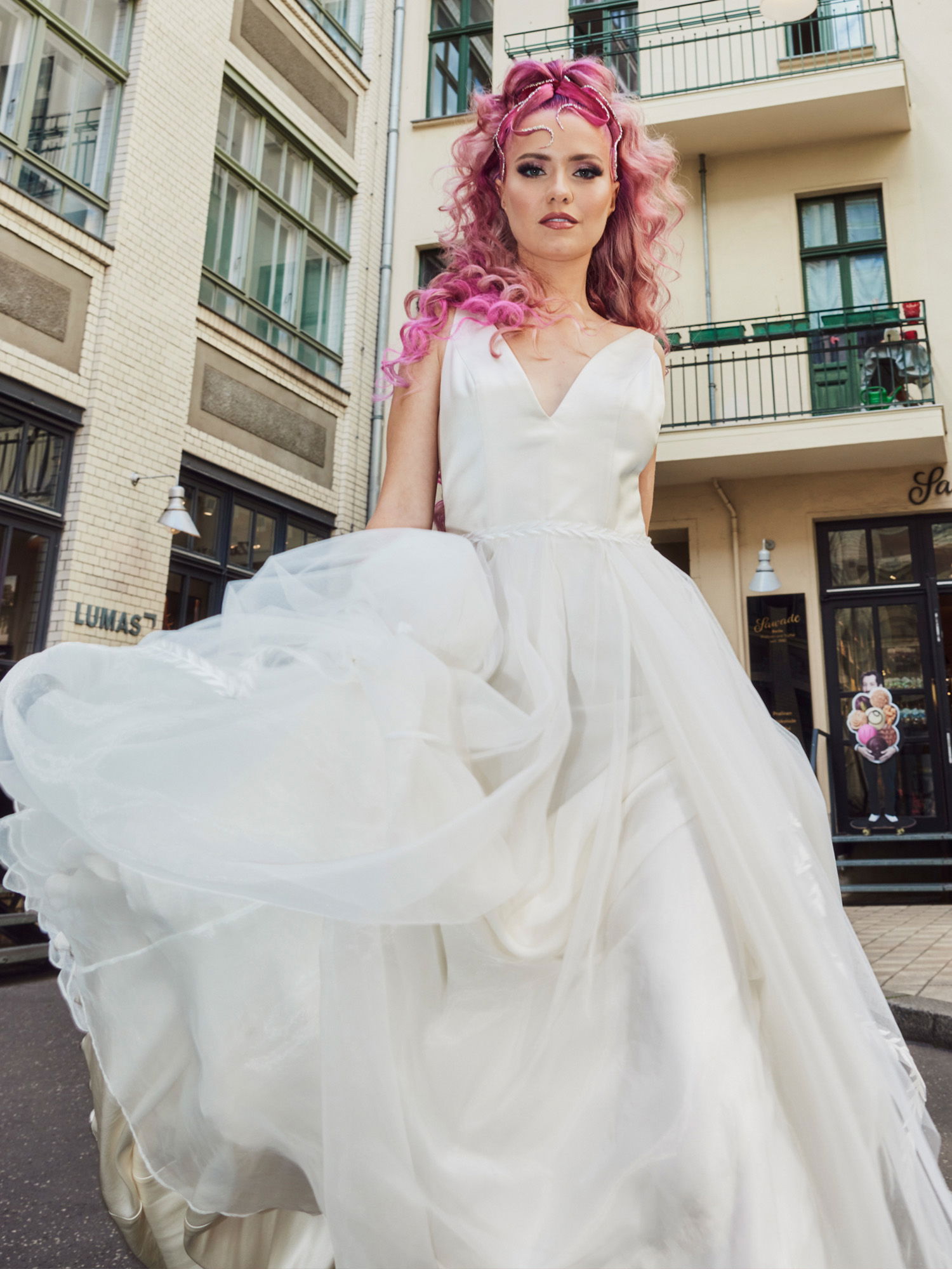 Braut im Hochzeitskleid mit rosa gefärbten Haaren posiert auf der Straße