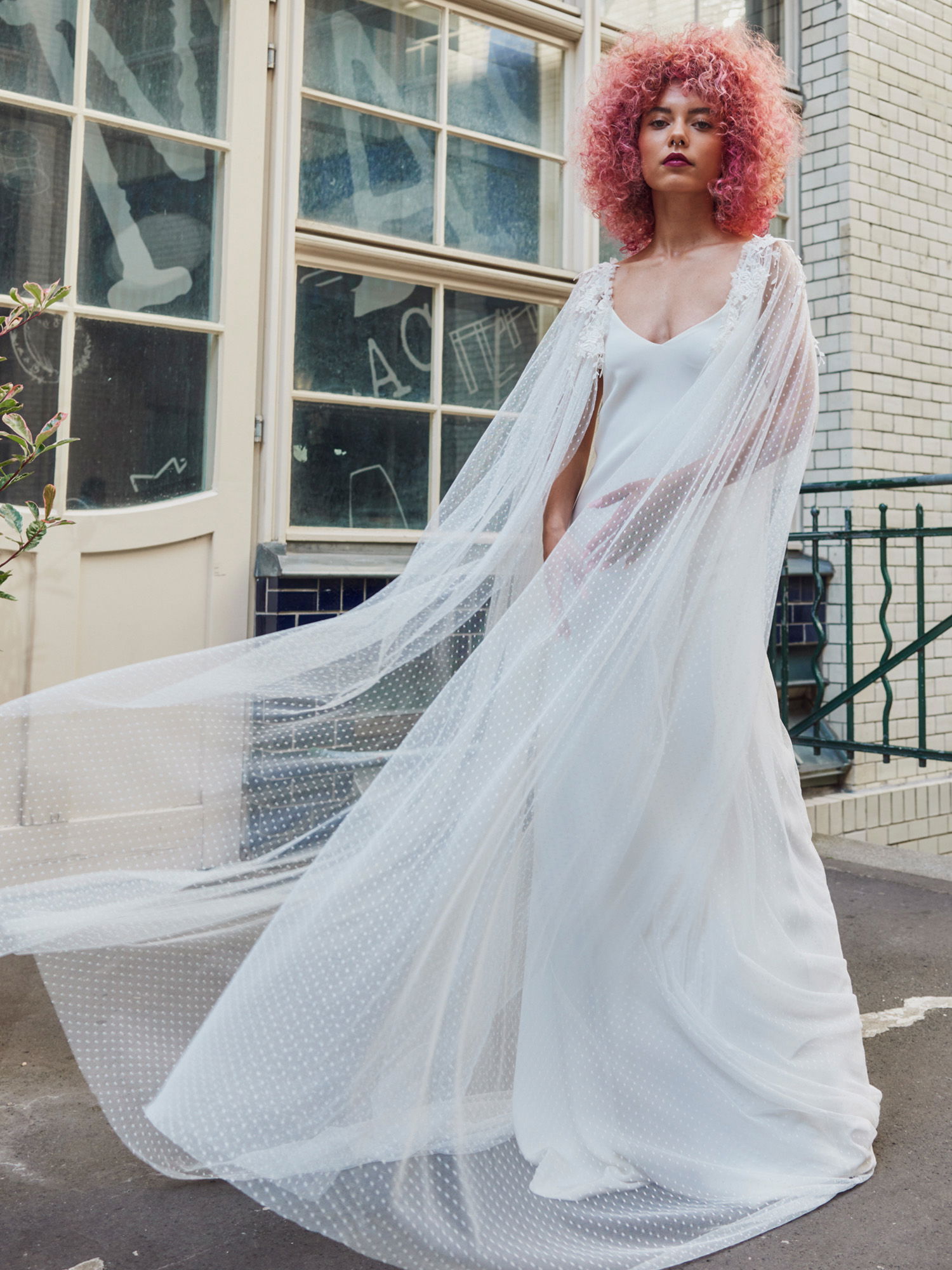 Braut im Hochzeitskleid mit rot gefärbten Haaren posiert auf der Straße