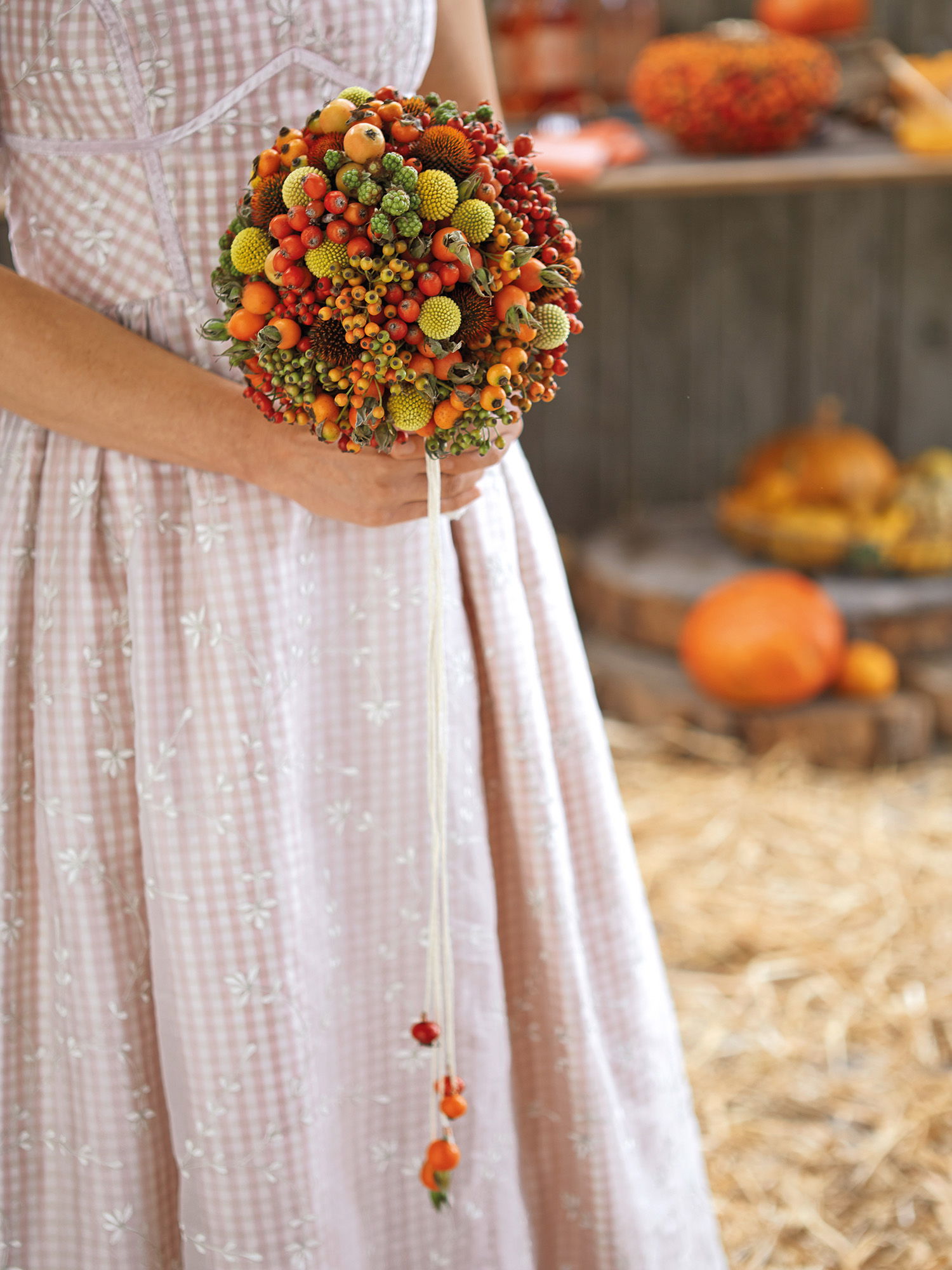 Detailaufnahme eines außergewöhnlichen Brautstraußes, der mit herbstlichen Früchten und Beeren in warmen, natürlichen Farben verziert ist.