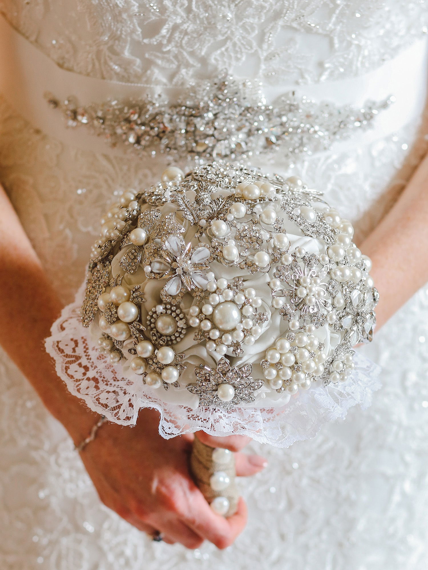 Nahaufnahme eines luxuriösen Brautstraußes aus Perlen und Kristallverzierungen, harmonisch abgestimmt mit dem Brautkleid.