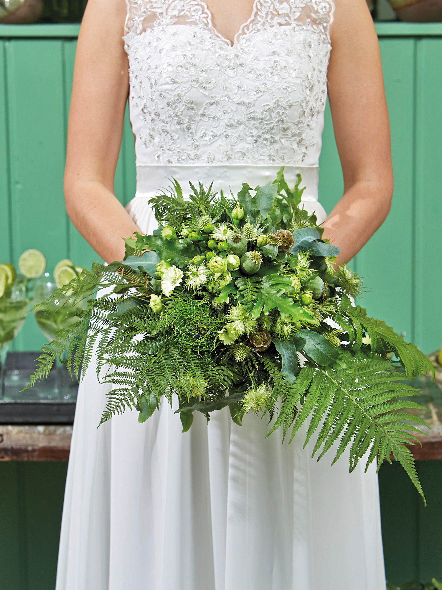 Der grüne Hochzeitsstrauß der Braut besteht aus Farnen, Disteln und weiteren grünen Akzenten. Die Blätter und Knospen verleihen dem Bouquet eine frische, natürliche Ausstrahlung.