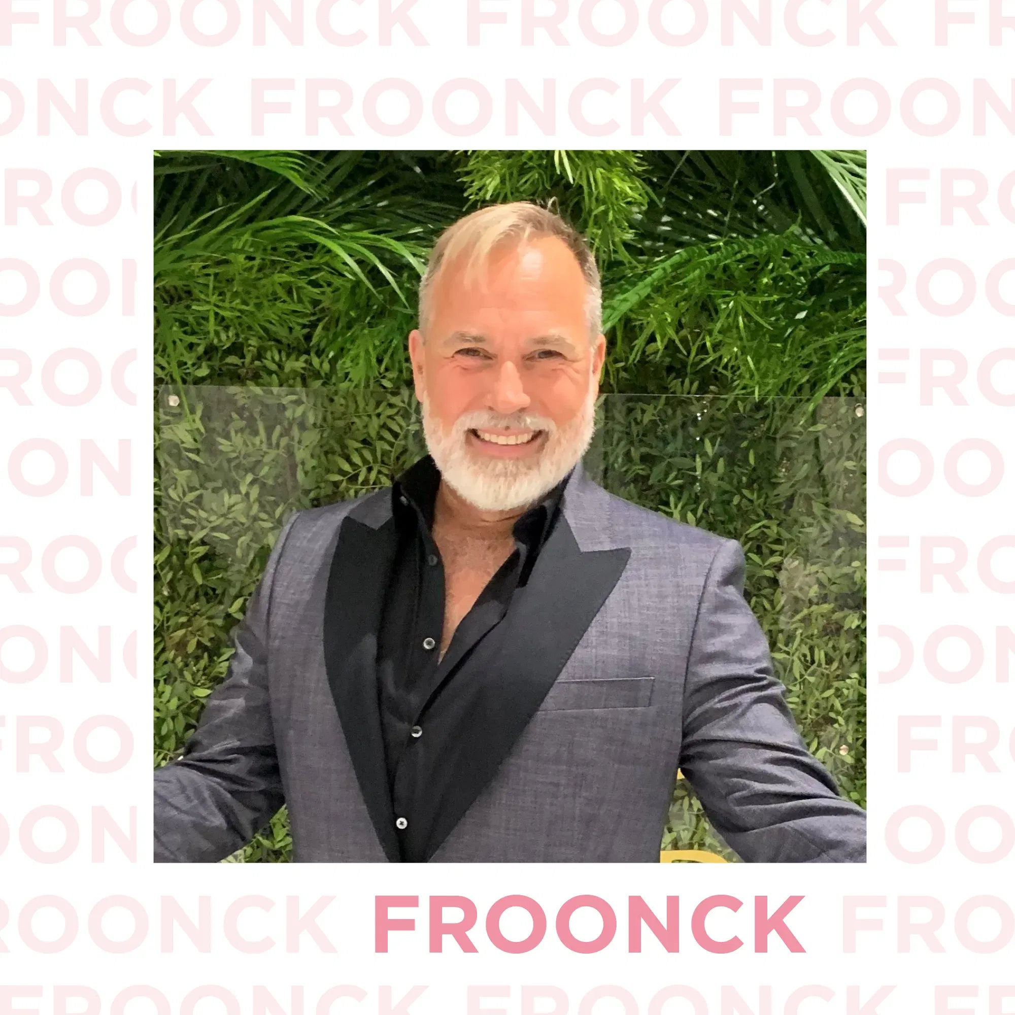 Froonck, ein bekannter Hochzeitsexperte, lächelt in einem grauen Anzug und schwarzen Hemd vor einer Wand aus Pflanzen. Sein freundlicher Ausdruck und die professionelle Kleidung vermitteln eine einladende Atmosphäre.