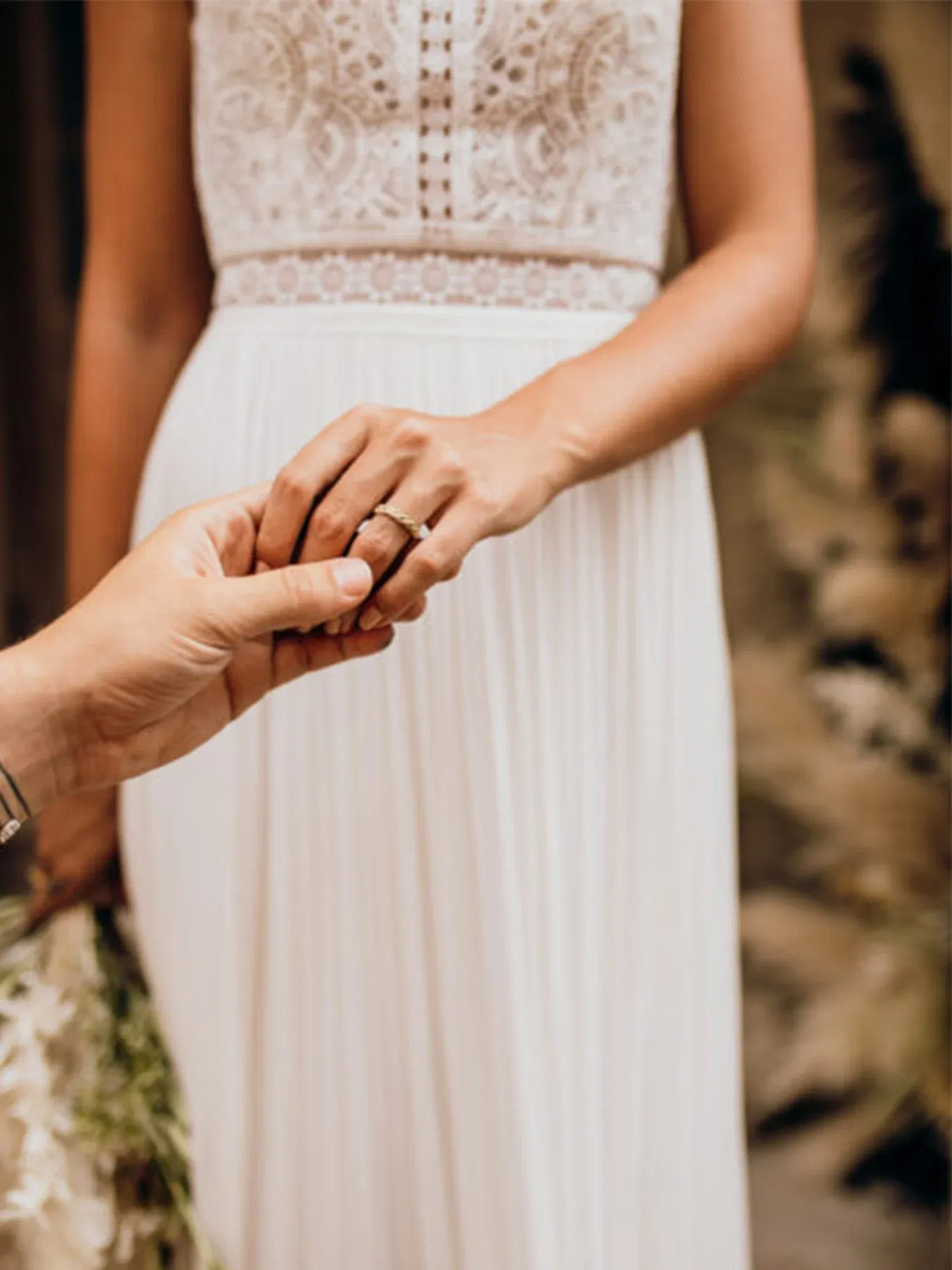 Nahaufnahme einer romantischen Trauung, bei der der Bräutigam der Braut behutsam den Ehering an den Finger steckt.