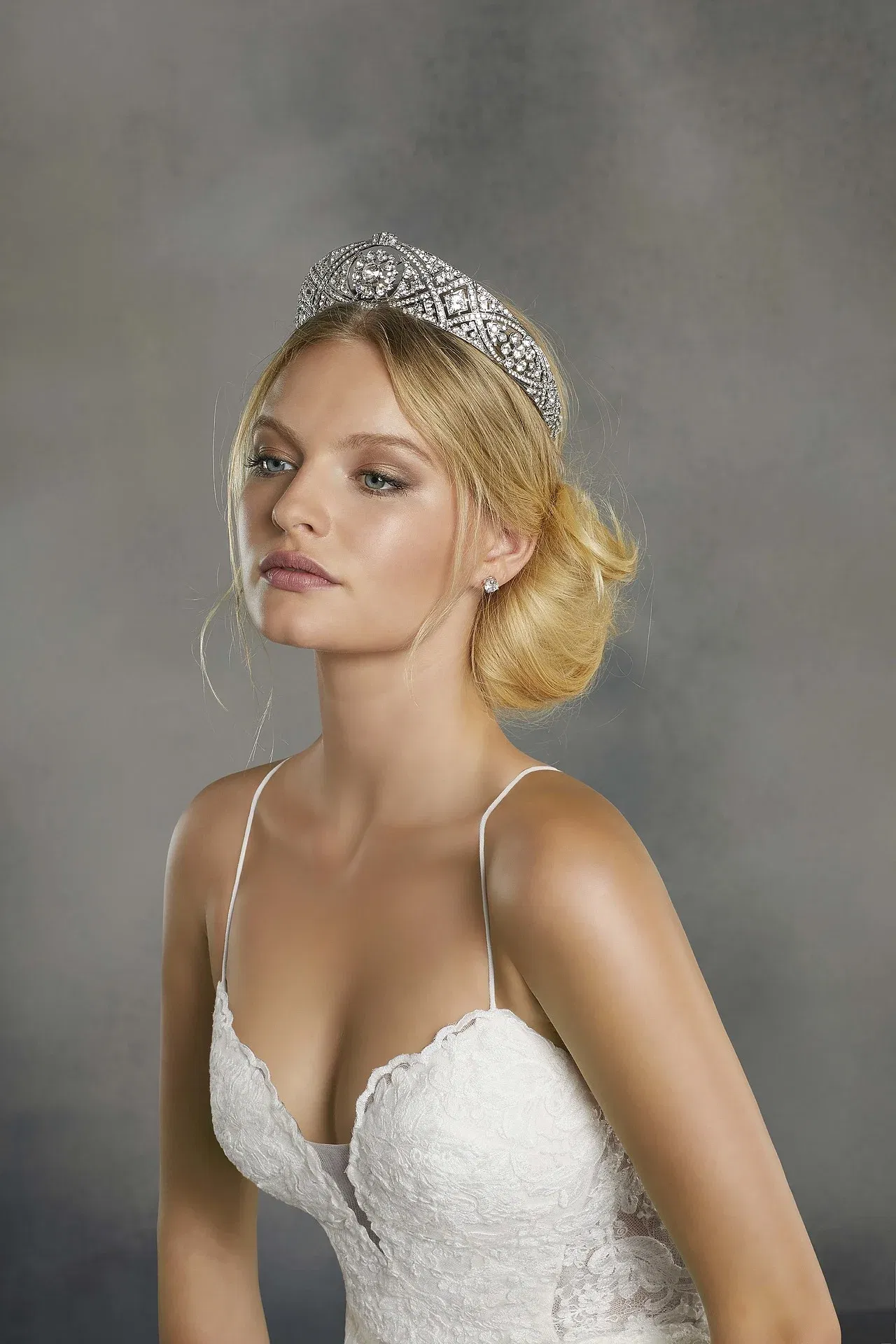 Die Braut trägt ein schlichtes Spitzenhochzeitskleid und eine elegante Tiara. Ihr Haar ist locker und stilvoll hochgesteckt.