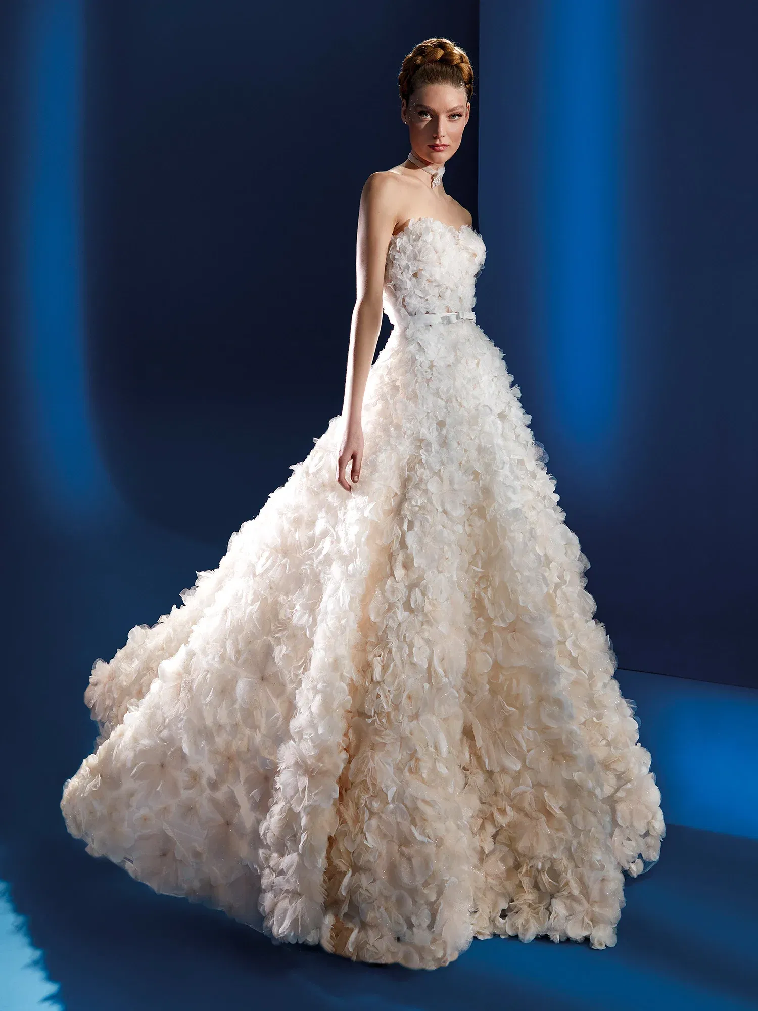 Elegantes, trägerloses Brautkleid mit einem ausgestellten Rock, der mit zarten, floralen Applikationen bedeckt ist. Der tiefe Ausschnitt und die detailreichen Blütenmuster verleihen dem Kleid eine märchenhafte Eleganz.