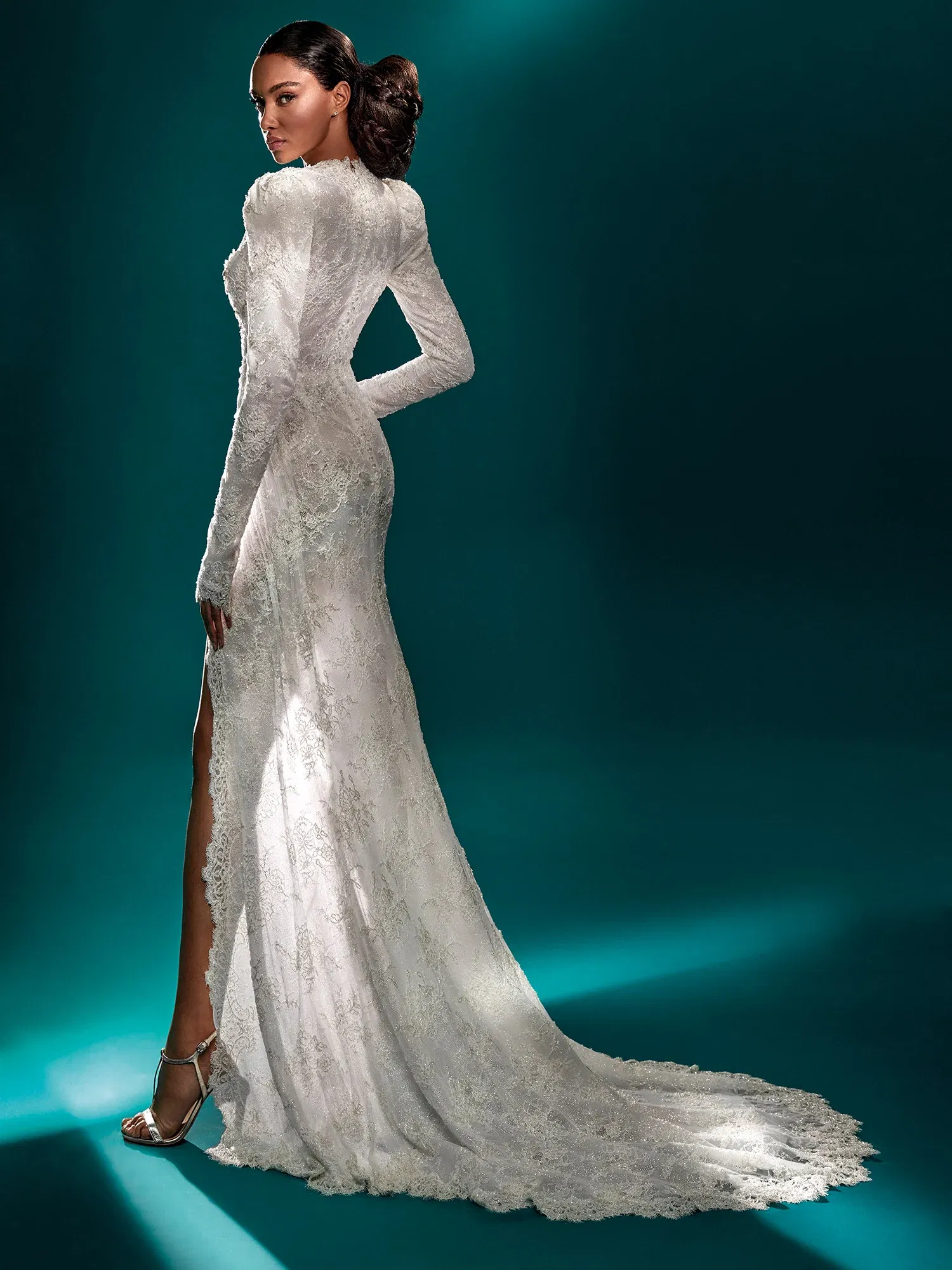 Elegantes, langärmliges Brautkleid mit feiner Spitze und schmaler Silhouette. Der Beinschlitz und die lange Schleppe schaffen einen verführerischen, doch klassischen Look, der die feminine Figur betont.