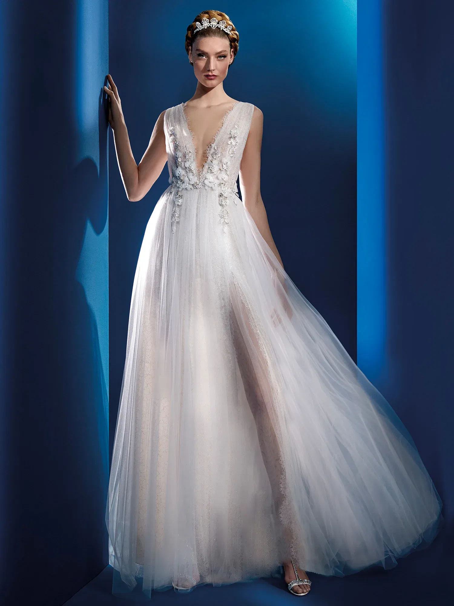 Elegantes Brautkleid mit tiefem Ausschnitt und feinen, floralen Applikationen. Der weiche Tüllrock fällt sanft und schafft eine luftige, verträumte Silhouette, während der tiefe Ausschnitt dem Design einen modernen, femininen Touch gibt.