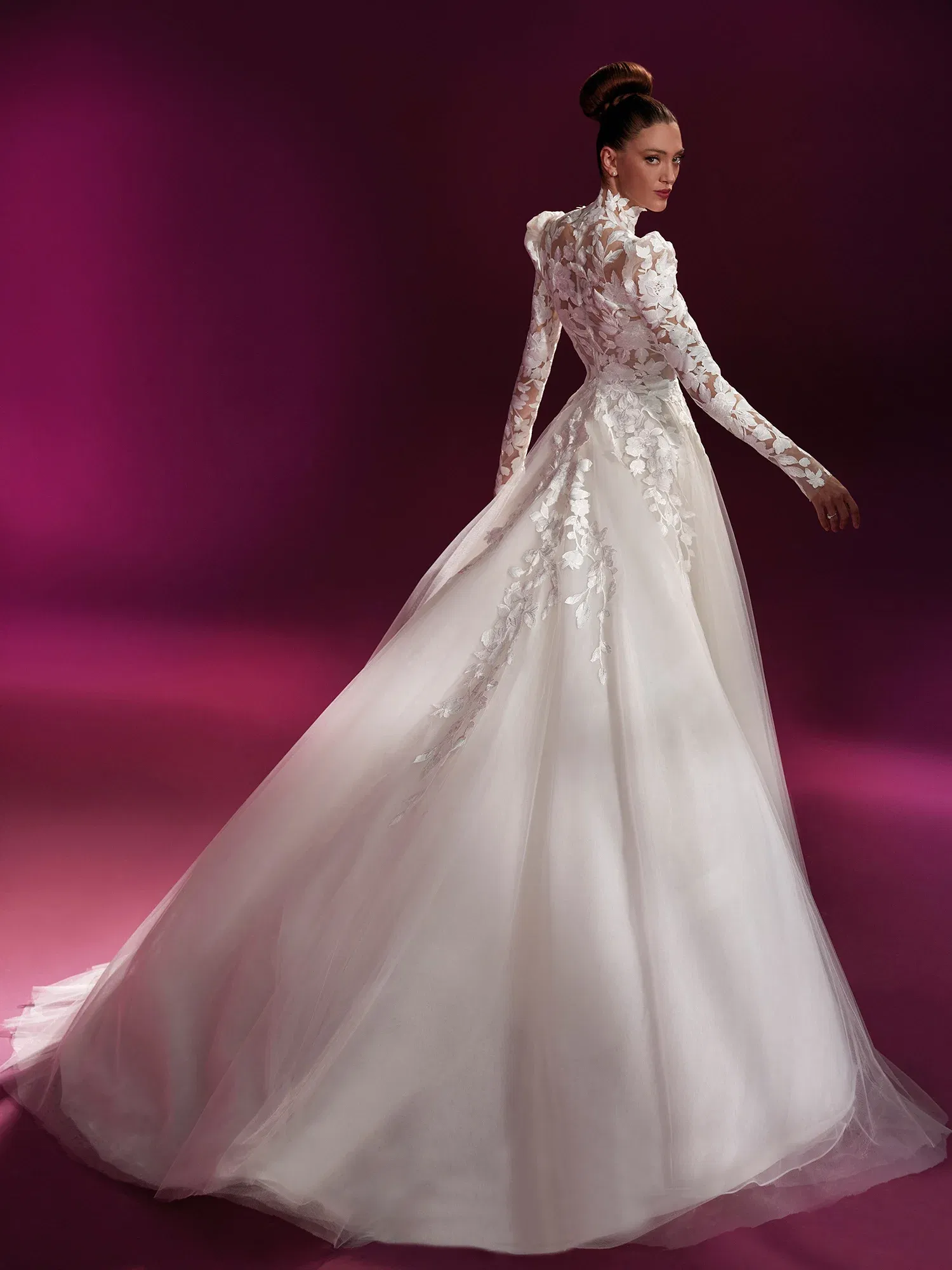 Elegantes Brautkleid mit hochgeschlossenem Rücken und durchsichtigen langen Ärmeln, verziert mit floraler Spitze. Der weite Tüllrock verleiht dem Kleid eine märchenhafte Anmutung, während die detaillierte Spitze feminine Akzente setzt.