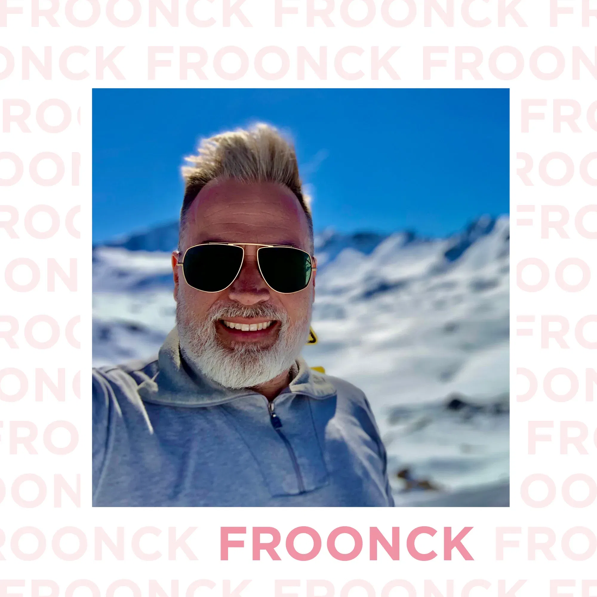 Froonck in Sonnenbrille, vor einer verschneiten Berglandschaft, lächelt in die Kamera, umgeben von blauem Himmel und hellem Schnee.