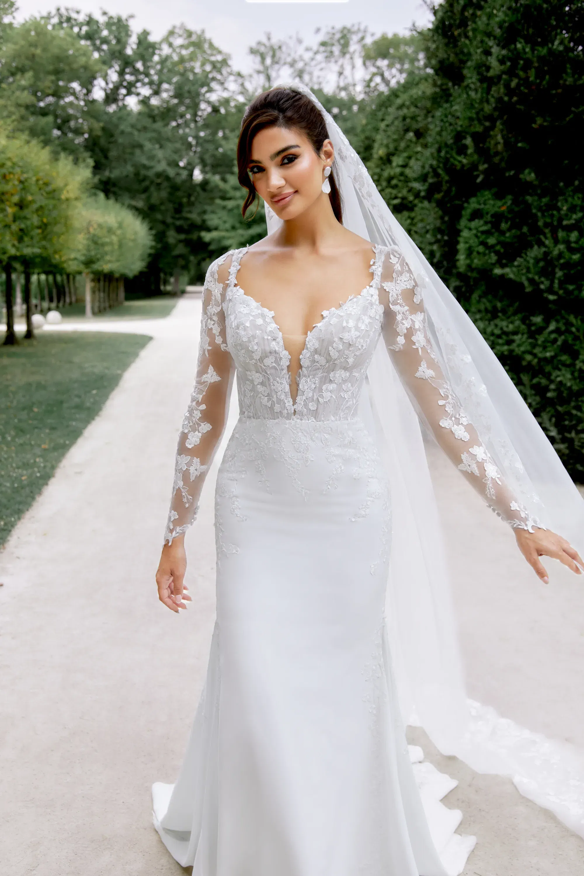 Nahaufnahme eines Brautkleides mit tiefem Ausschnitt und floralen Spitzenapplikationen – ergänzt durch einen langen Schleier.