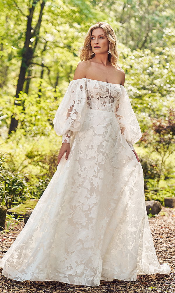 Zartes Kleid mit voluminösen Ärmeln und transparenter Spitze, perfekt für eine Boho-Hochzeit im Grünen.