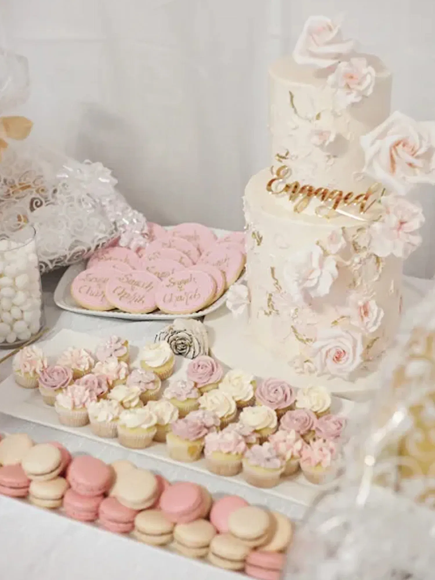 Süße Leckereien bei einer Verlobungsfeier: Mehrstöckige Torte, Macarons und Cupcakes in rosa und weiß.