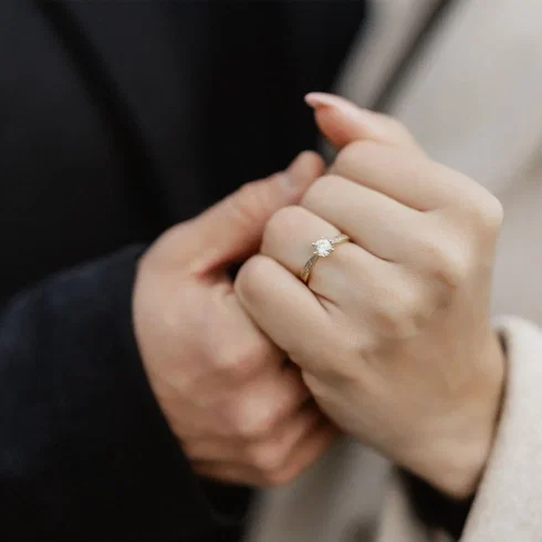 Frisch angesteckter Verlobungsring an der Hand der Frau, während das Paar sich nah gegenübersteht