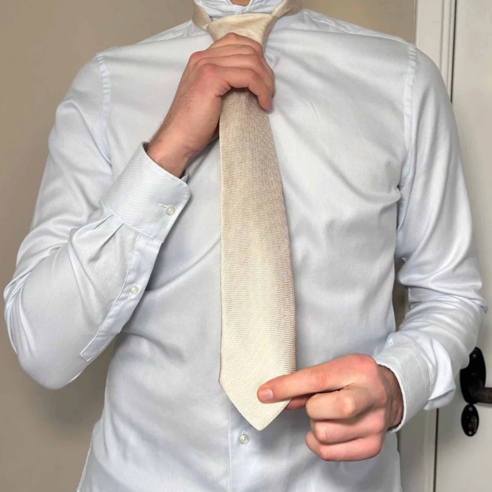 Der Krawattenknoten wird vorsichtig festgezogen und nach oben geschoben.