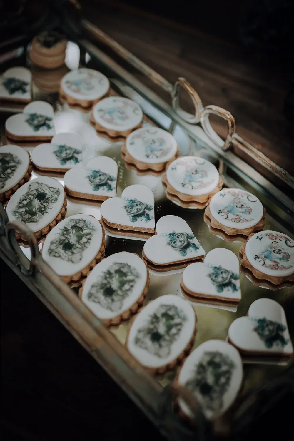 Eine Auswahl an kunstvoll dekorierten Keksen in Herz- und Ovalform, die auf einem Tablett mit thematischen Motiven präsentiert werden.