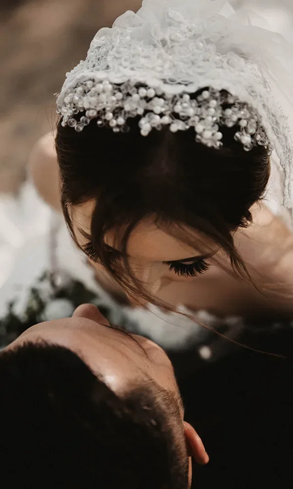 Ein zärtlicher Moment zwischen Braut und Bräutigam, aus der Vogelperspektive aufgenommen. Die Braut mit kunstvollem Schleier lehnt sich liebevoll zu ihrem Ehemann, der nach oben schaut.