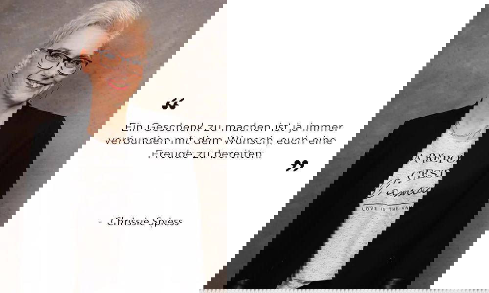 Porträt von Chrissie Spiess in lässigem Look mit Statement-Shirt und schwarzer Jacke. In ihrem Zitat betont sie, dass Geschenke immer mit einem liebevollen Gedanken verbunden sind.