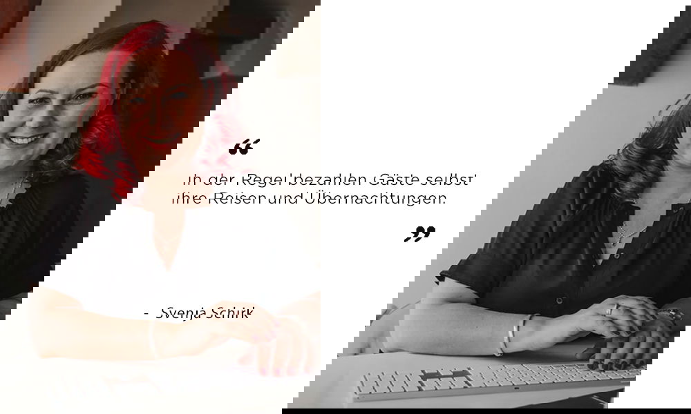 Porträt von Svenja Schirk mit roten Locken, schwarzer Bluse und dezentem Schmuck, aufgenommen in einem modernen Raum. In ihrem Zitat erklärt sie, dass Hochzeitsgäste meist ihre Anreise und Unterkunft selbst zahlen.