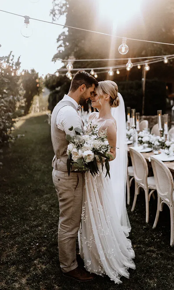 Hochzeitpaar in einem Garten vor einem gedeckten Tisch