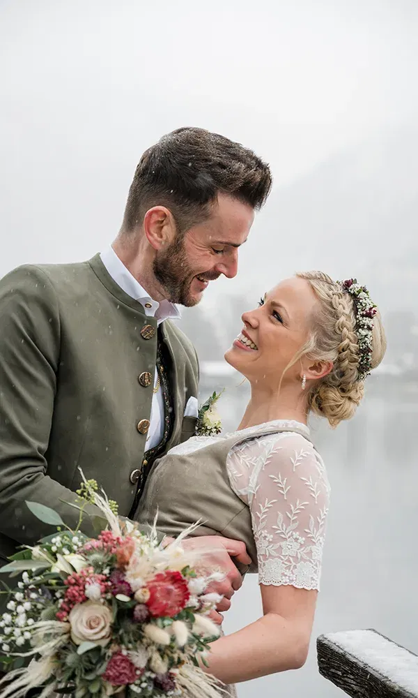 Hochzeitspaar beim Fotoshooting vor einem See mit Bergen