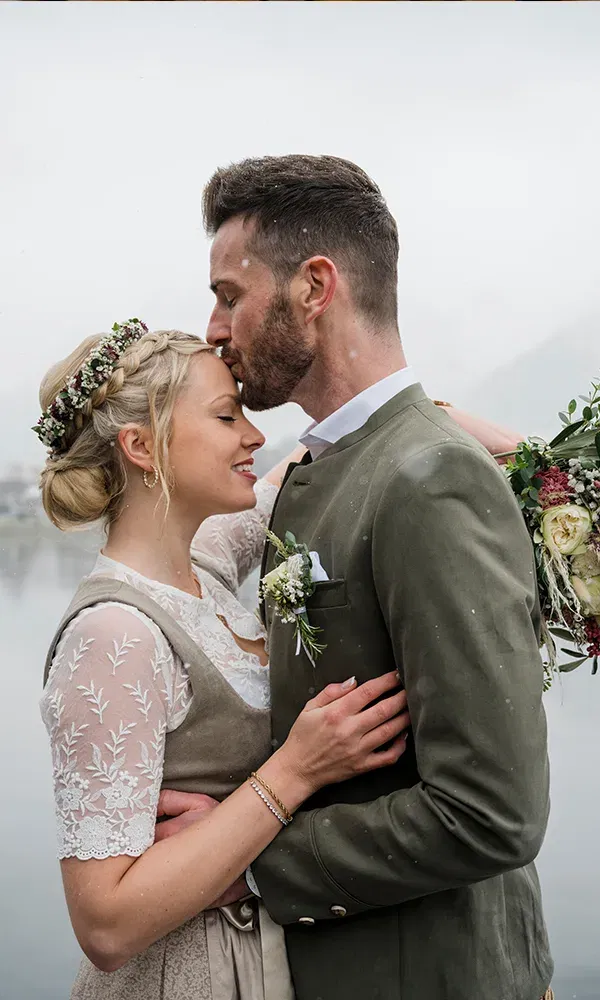 Hochzeitspaar beim Fotoshooting vor einem See mit Bergen