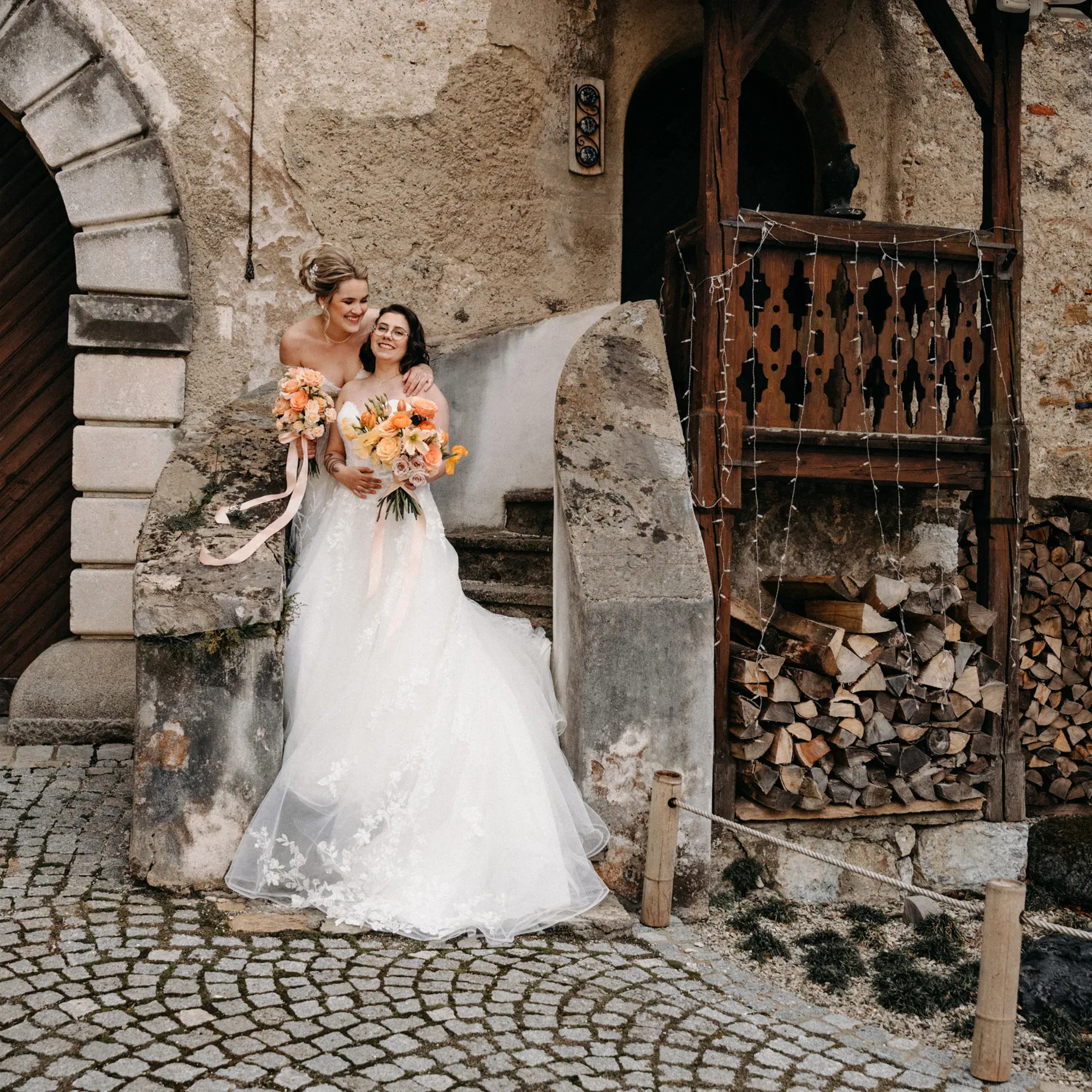 Romantisches Hochzeitsfoto eines Brautpaars in Weiß, aufgenommen vor einer malerischen historischen Kulisse.