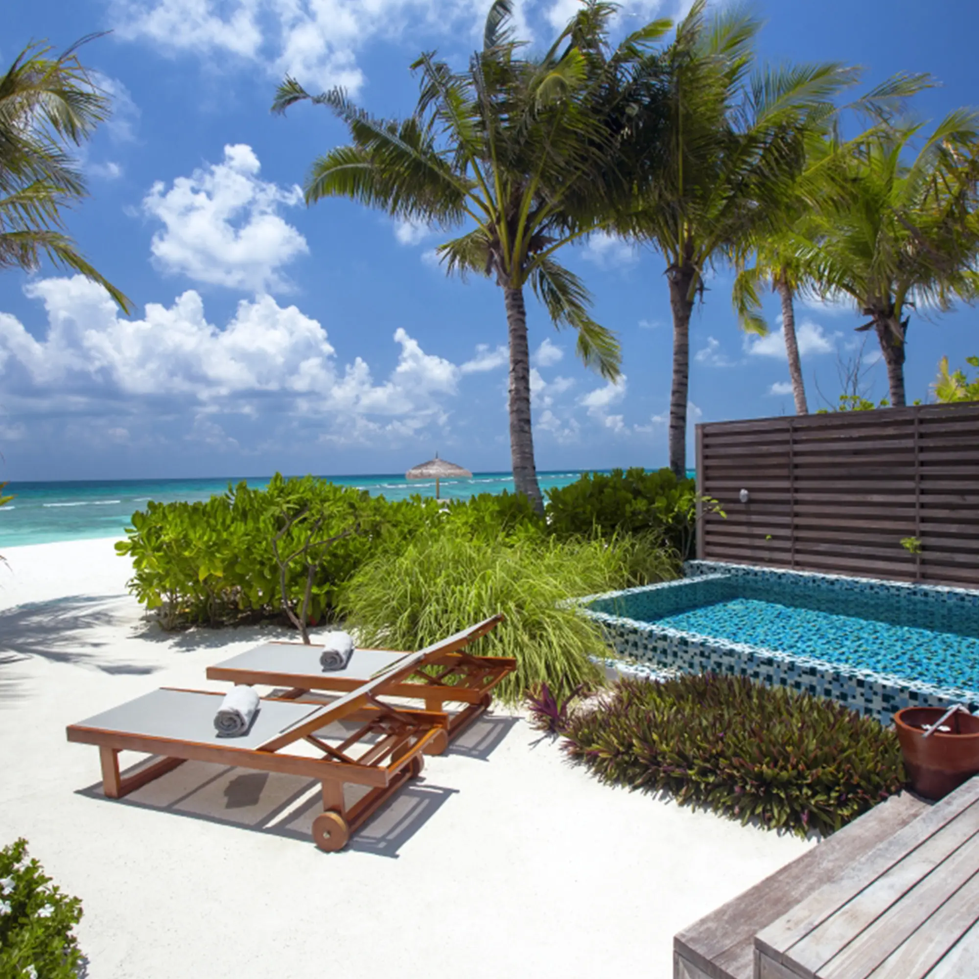 Einladende Strandvilla umgeben von üppigem Grün, mit privatem Pool und Sonnendeck, wenige Schritte vom weißen Sandstrand entfernt.