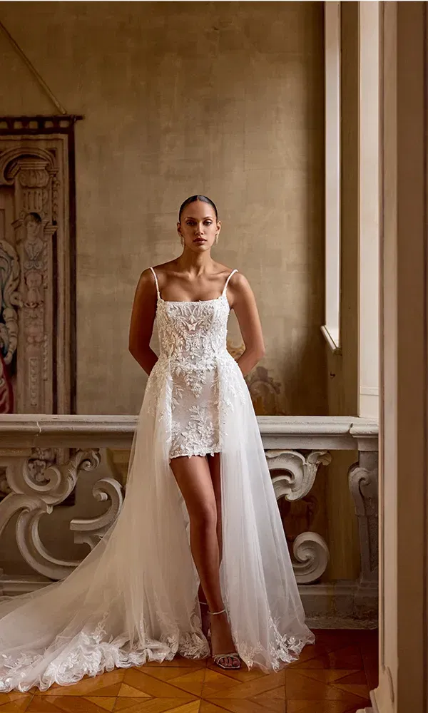 Spitzenkleid im Mermaid-Stil mit trägerlosem Ausschnitt, aufgenommen auf einer steinernen Treppe mit mediterranem Charme.