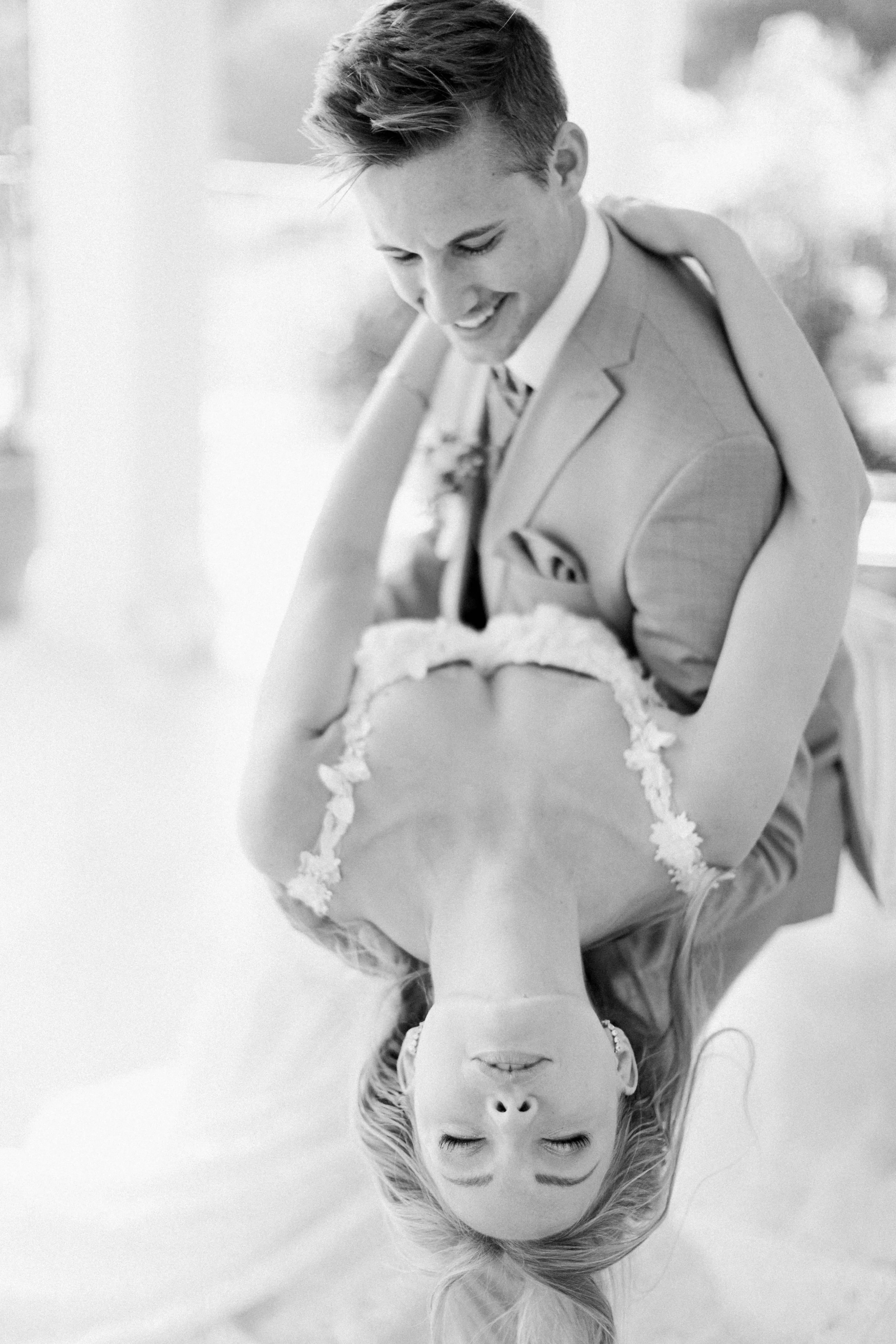 Ein intimer Moment zwischen Braut und Bräutigam, die sich während eines romantischen Tanzes ansehen, festgehalten in Schwarz-Weiß.