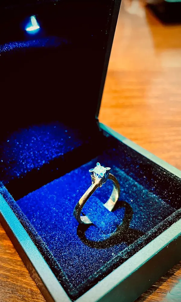 Ein funkelnder Verlobungsring mit Solitär-Diamant, elegant präsentiert in einer geöffneten blauen Schmuckbox.