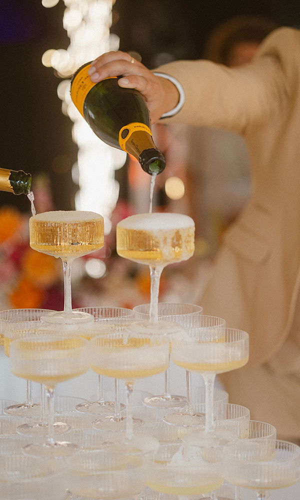 Detailaufnahme eines Champagner-Turms mit funkelnden Lichtern im Hintergrund.