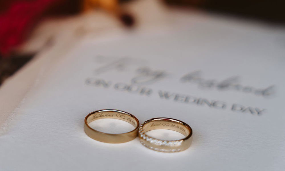 Nahaufnahme von Eheringen mit individueller Gravur auf einer Hochzeitskarte.