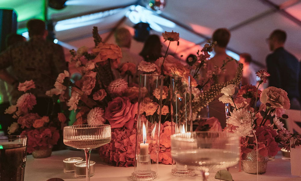 Detailreiche Blumendekoration in kräftigen Farben, beleuchtet durch zarte Kerzenflammen.