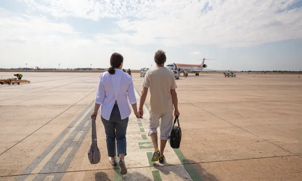 Zwei Menschen laufen gemeinsam über die Startbahn, Taschen in der Hand, mit Blick auf ein wartendes Passagierflugzeug.