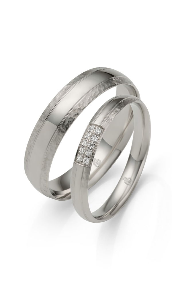 Modernes Trauring-Set in Weißgold mit strukturierter Oberfläche. Während der Herrenring eine klassische, minimalistische Optik besitzt, besticht der Damenring mit einer funkelnden Diamantreihe.
