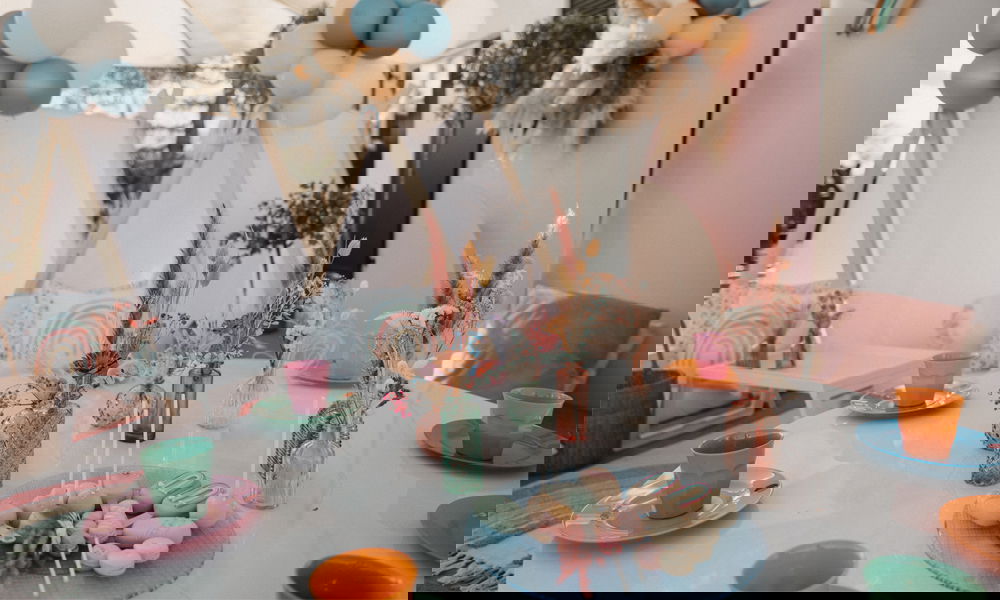 Lebhafte Tischdekoration mit Trockenblumen in Vasen, Regenbogen-Details und Ballons, perfekt für eine Kinderparty oder entspannte Gartenfeste.