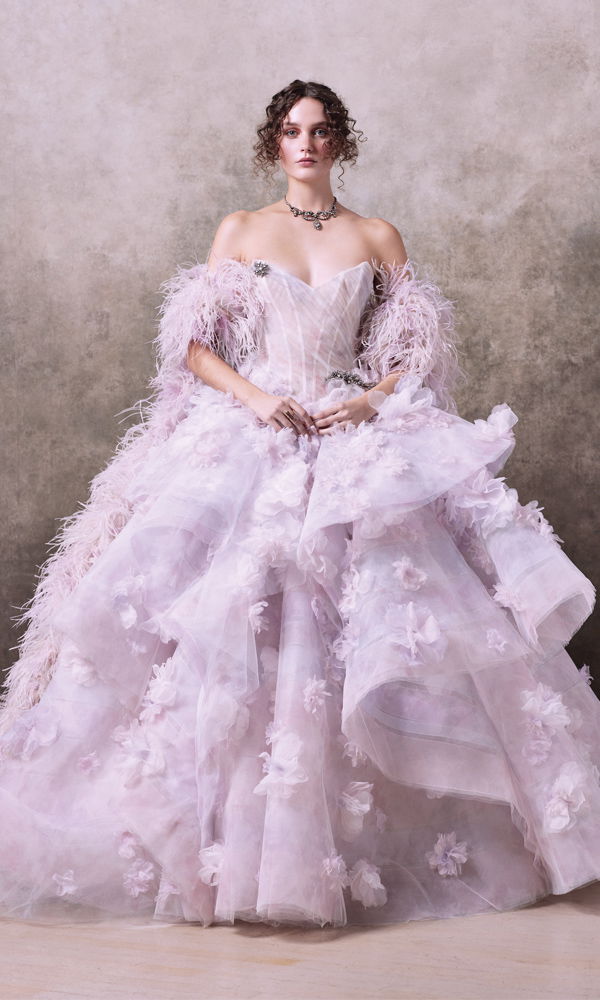 Luxuriöses Hochzeitskleid mit mehrlagigem Tüllrock, kunstvollen Blütenapplikationen und einem glamourösen Federbolero. Das schulterfreie Design sorgt für einen eleganten, königlichen Auftritt.