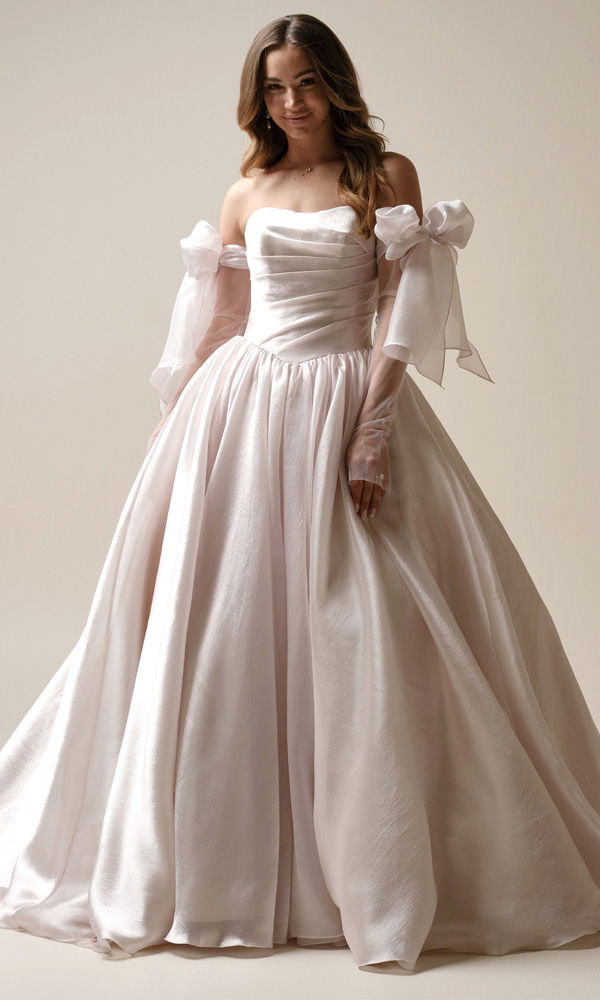 Braut in einem voluminösen, schimmernden Ballkleid mit Herzausschnitt und verspielten Details an den Ärmeln – femininer Look für die Traumhochzeit.