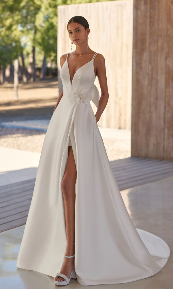 Modernes Hochzeitskleid mit fließendem Rock und romantischen Details, kombiniert mit Spaghetti-Trägern und femininer Silhouette.