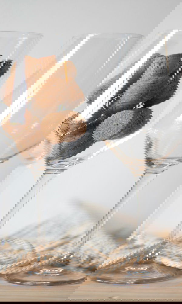 Minimalistisches Arrangement mit Weingläsern und Korken, kombiniert mit natürlichem Seil und Holzuntergrund, ideal für Boho-Dekoration.