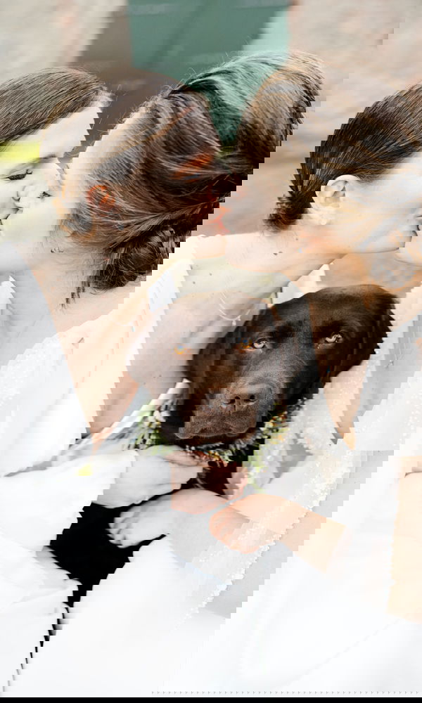 Romantisches Hochzeitsbild mit zwei Bräuten und einem Labrador, liebevoll geschmückt mit einem Blumenschmuck für die Zeremonie.