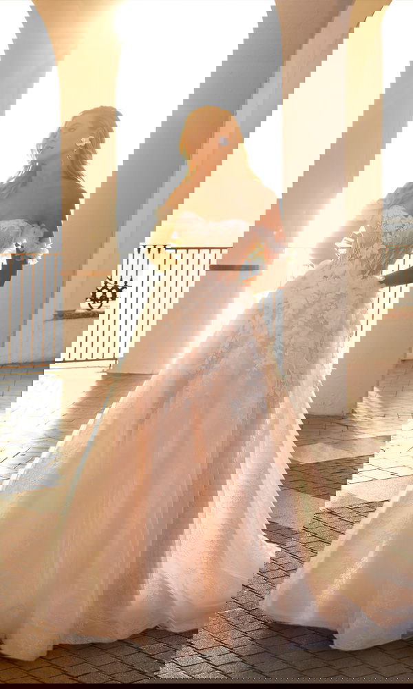 A-Linien-Brautkleid mit zarter Spitze, abnehmbaren Trägern und floralen Applikationen – fotografiert bei goldener Abendsonne.