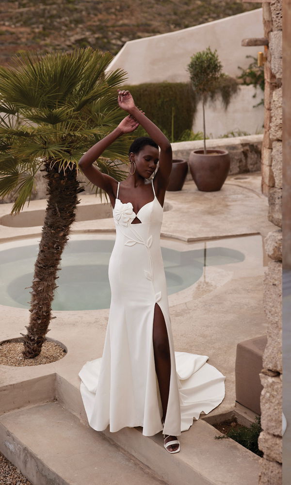 Modernes Hochzeitskleid mit minimalistischem Design, zarten Blumenakzenten und sinnlicher Silhouette, aufgenommen in einer eleganten Outdoor-Kulisse.