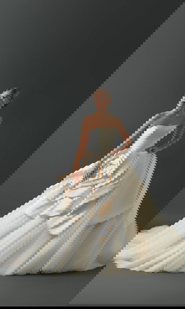 Glamouröses Hochzeitskleid mit trägerlosem Oberteil und einer auffälligen, kunstvollen Blumenapplikation, ideal für eine opulente Zeremonie.